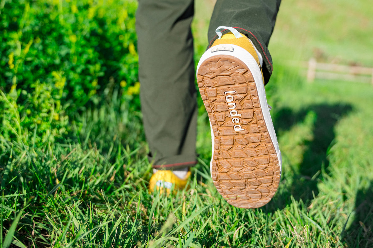 Close-up of a Landed Overlook sneaker stepping through green grass