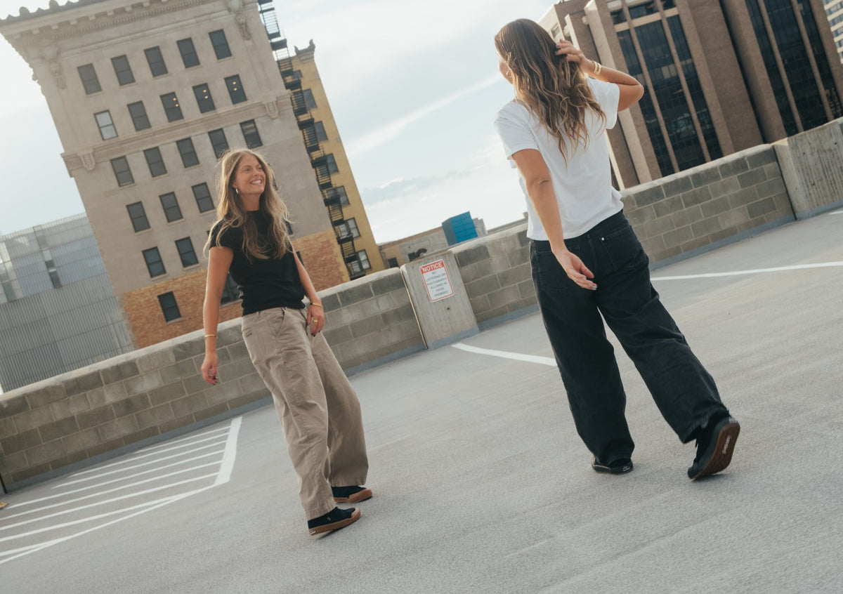 Two friends walking across a downtown rooftop parking deck in Landed sneakers
