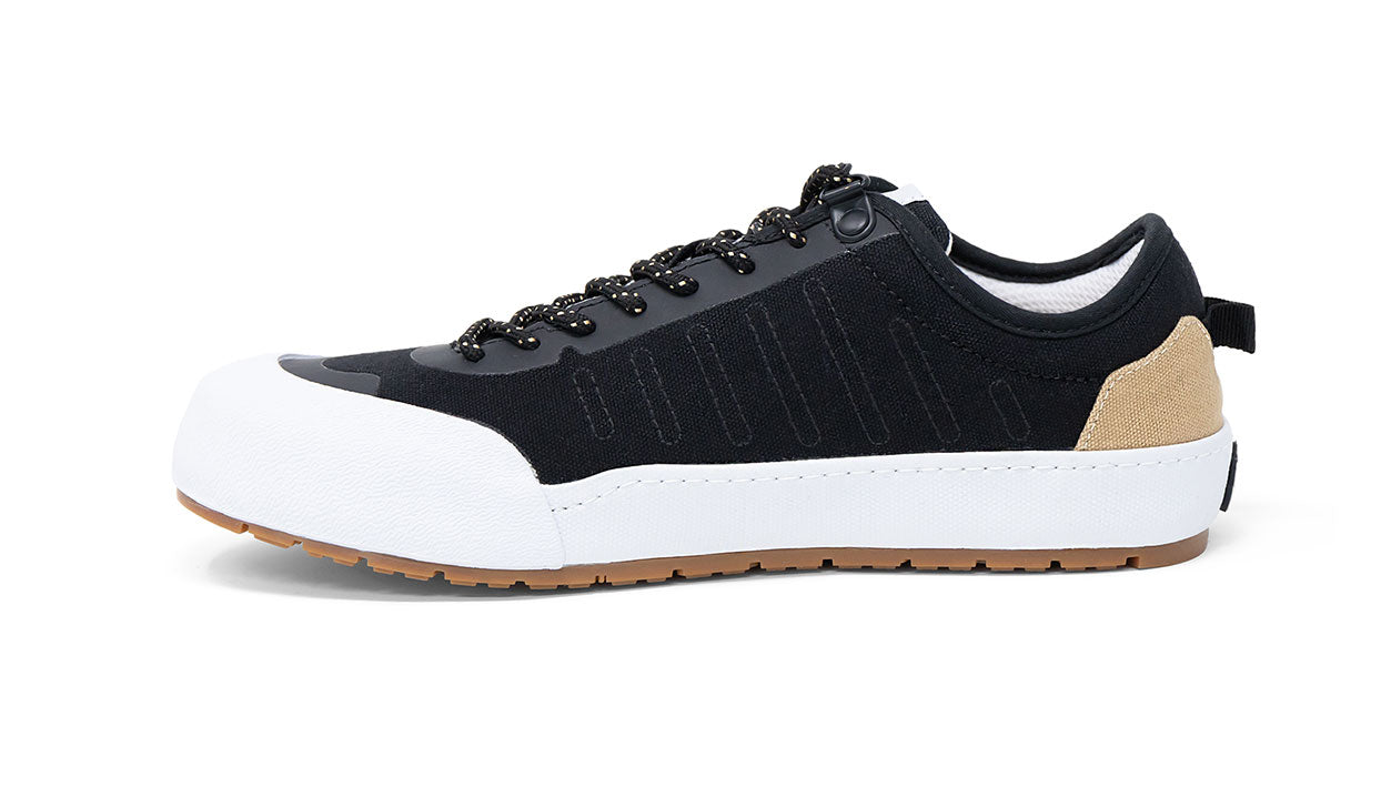 Landed The Overlook 1.0 black technical sneaker with white rubber toe cap, tan heel detail, and gum rubber sole.