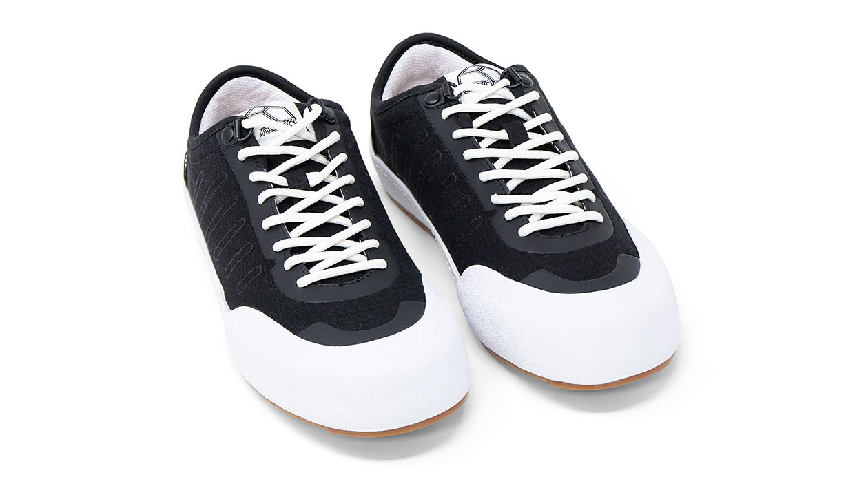 Landed The Overlook 1.0 black technical sneakers with white laces and a white rubber toe cap on a white background.