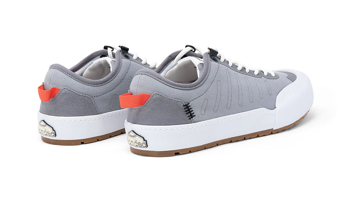 Landed The Overlook 1.0 grey canvas technical sneakers with white soles and orange heel pull tabs, rear view