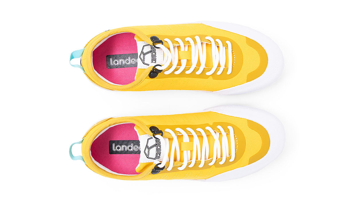 Top view of Landed The Overlook 1.0 yellow technical sneakers with white laces and pink insoles on white background